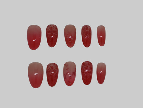 Set of red ombre nails with kimono pattern and color changing glitter vines on a white background