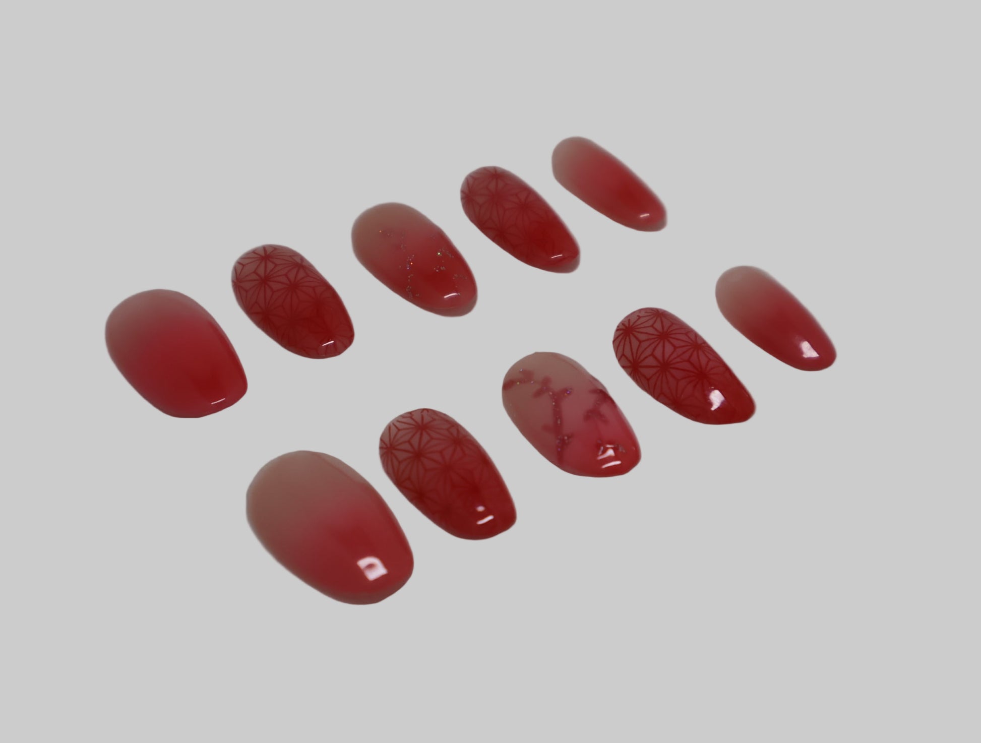 Set of red ombre nails with kimono pattern and color changing glitter vines on a white background