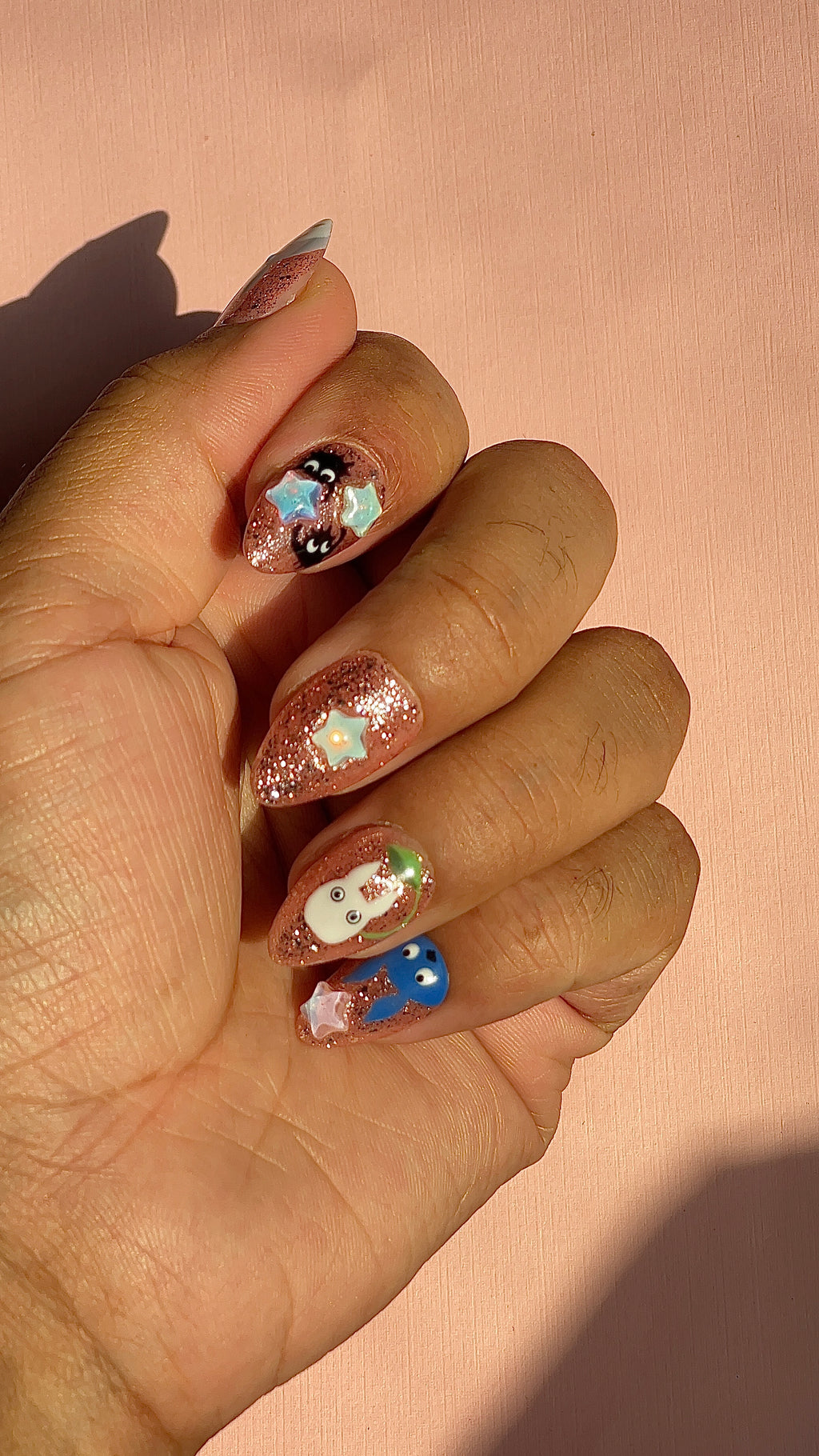 Whimsical rose-gold glitter press-on nails with 3D star charms and hand-painted forest creature designs. Dreamy, nostalgic and anime-inspired.