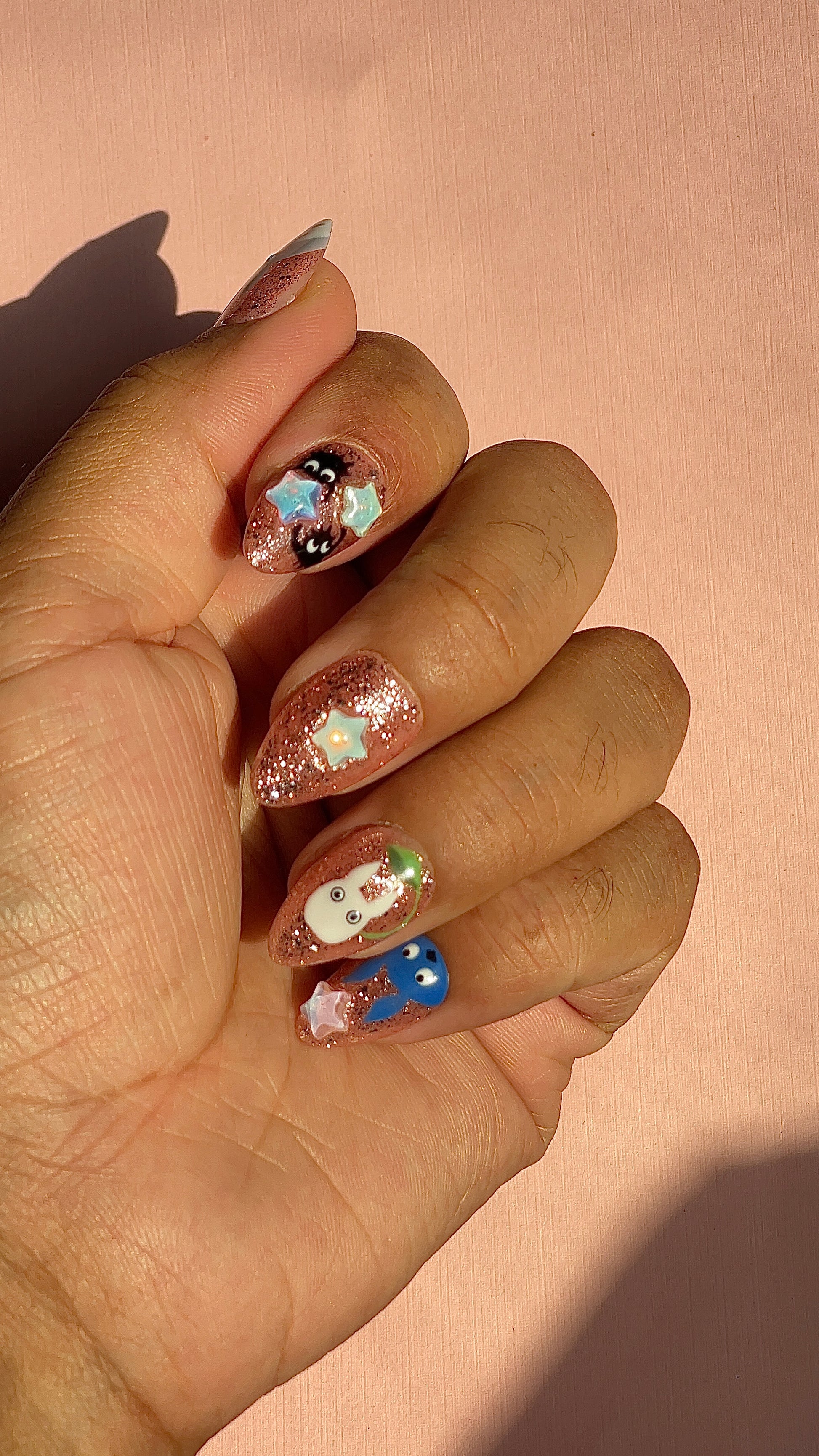 Whimsical rose-gold glitter press-on nails with 3D star charms and hand-painted forest creature designs. Dreamy, nostalgic and anime-inspired.