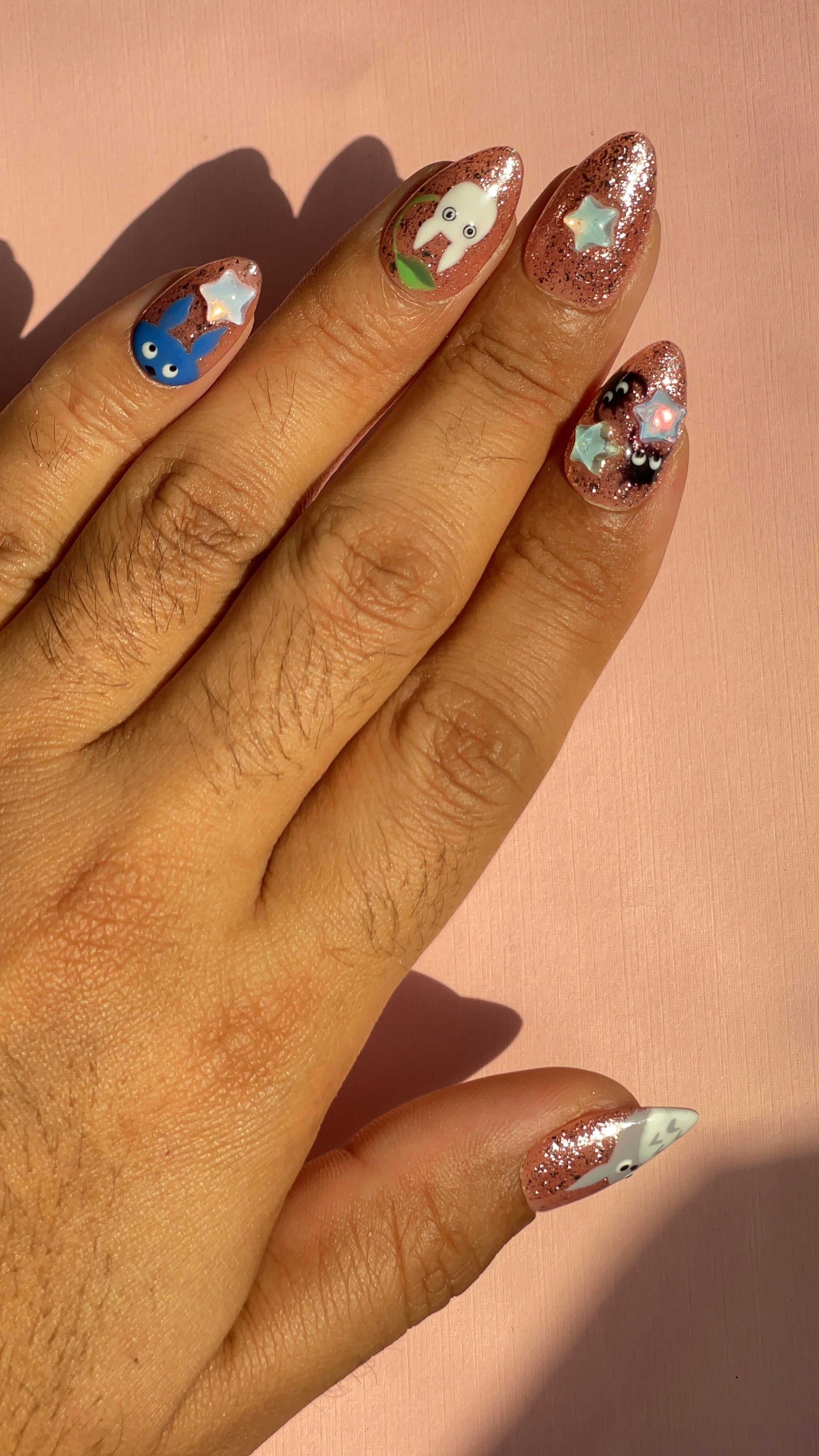 Whimsical rose-gold glitter press-on nails with 3D star charms and hand-painted forest creature designs. Dreamy, nostalgic and anime-inspired.